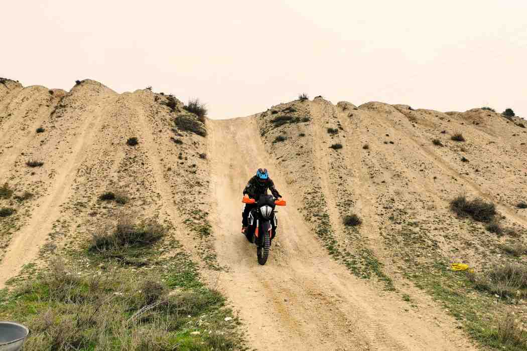 moto trail bajando una cuesta empinada en el curso de tecnificacion trail
