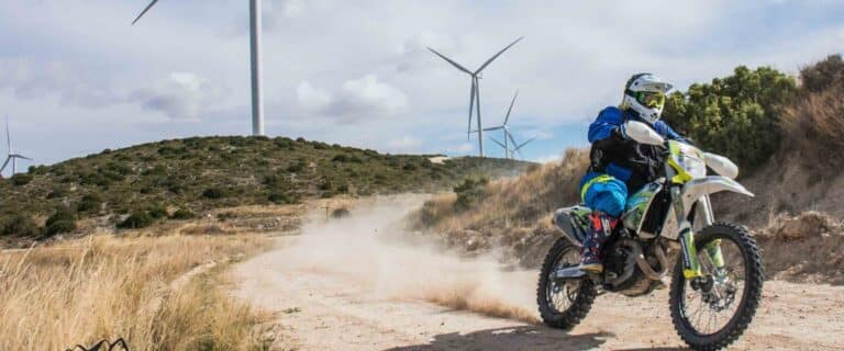 Motorista con una moto trail en una pista de tierra